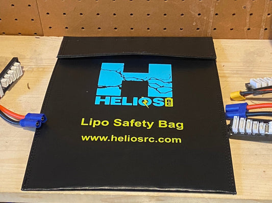 A black flat-style Lipo safety bag with the Helios RC logo in blue and yellow, along with two pass-throughs for battery leads.