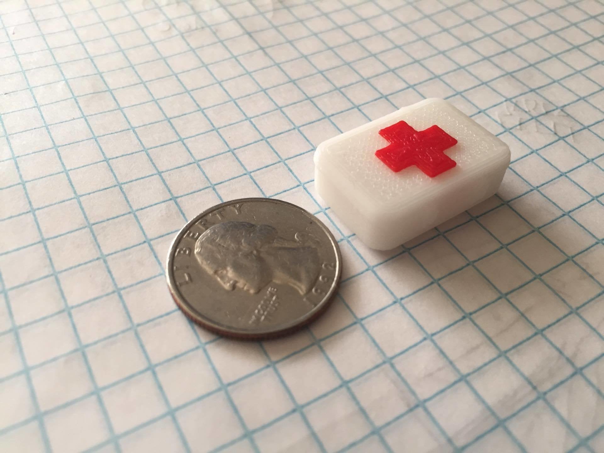 miniature scale first aid kit next to a quarter for scale