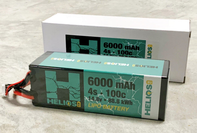 Two stacked rectangular lithium polymer battery packs with green and black coloring and branding details, indicating a capacity of 6000 mAh and 100C discharge rate.